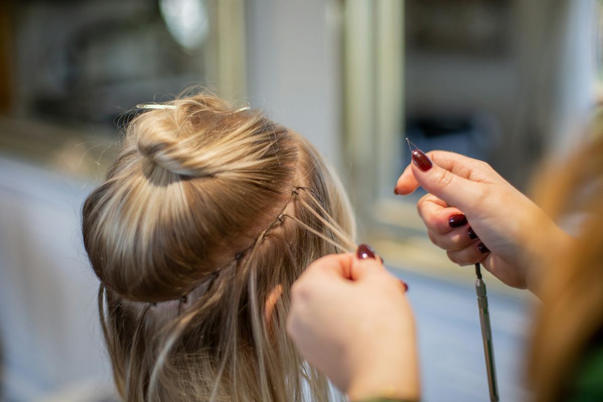 Handen werken blond haar op tot een knot