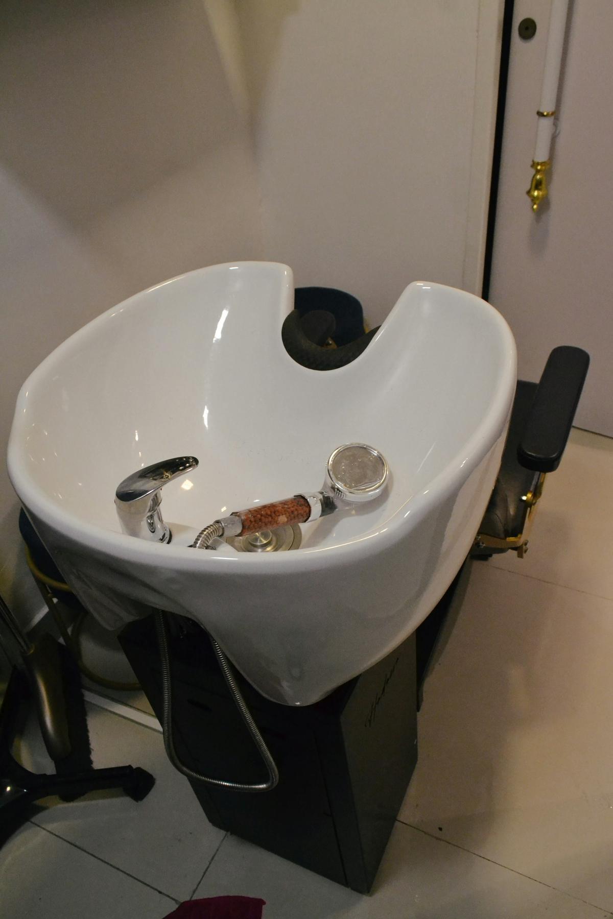 Witte wasbak met chromen kraan en handdouche in een kapsalon